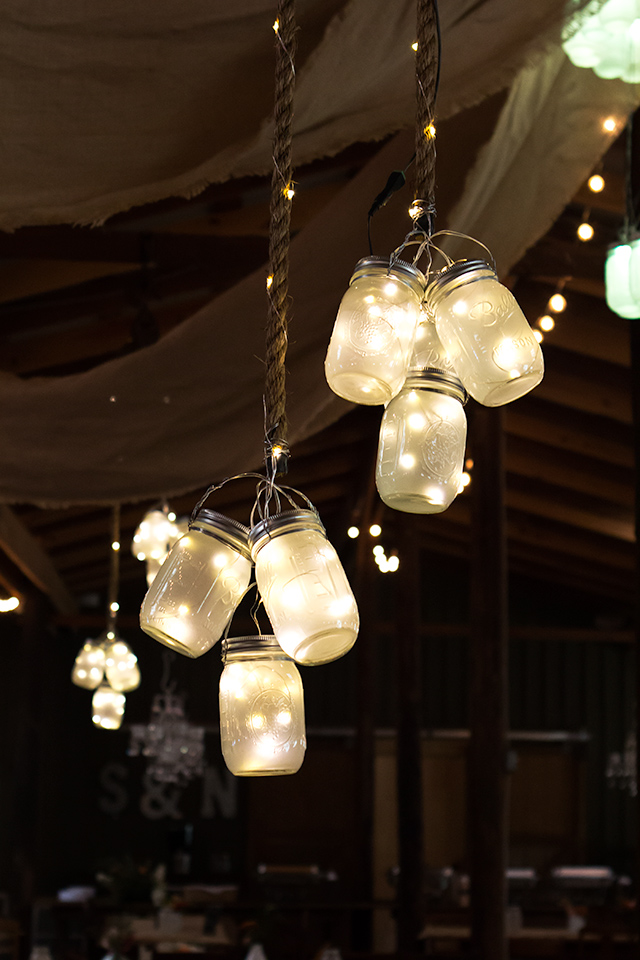 Clusters of frosted LED mason jar lights hung from the ceiling at this rustic barn wedding. So gorgeous and magical!